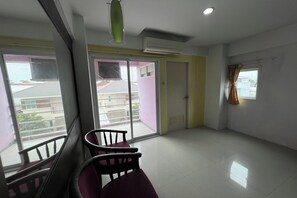 A room with a balcony, a chair, and a window with curtains. - Pongsatorn Mansion by Zuzu (Bangkok)
