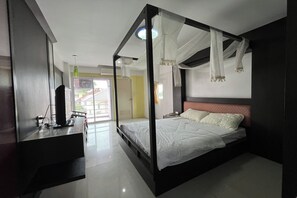 A bedroom with a four-poster bed, a desk with a computer, and a view of the outside. - Pongsatorn Mansion by Zuzu (Bangkok)