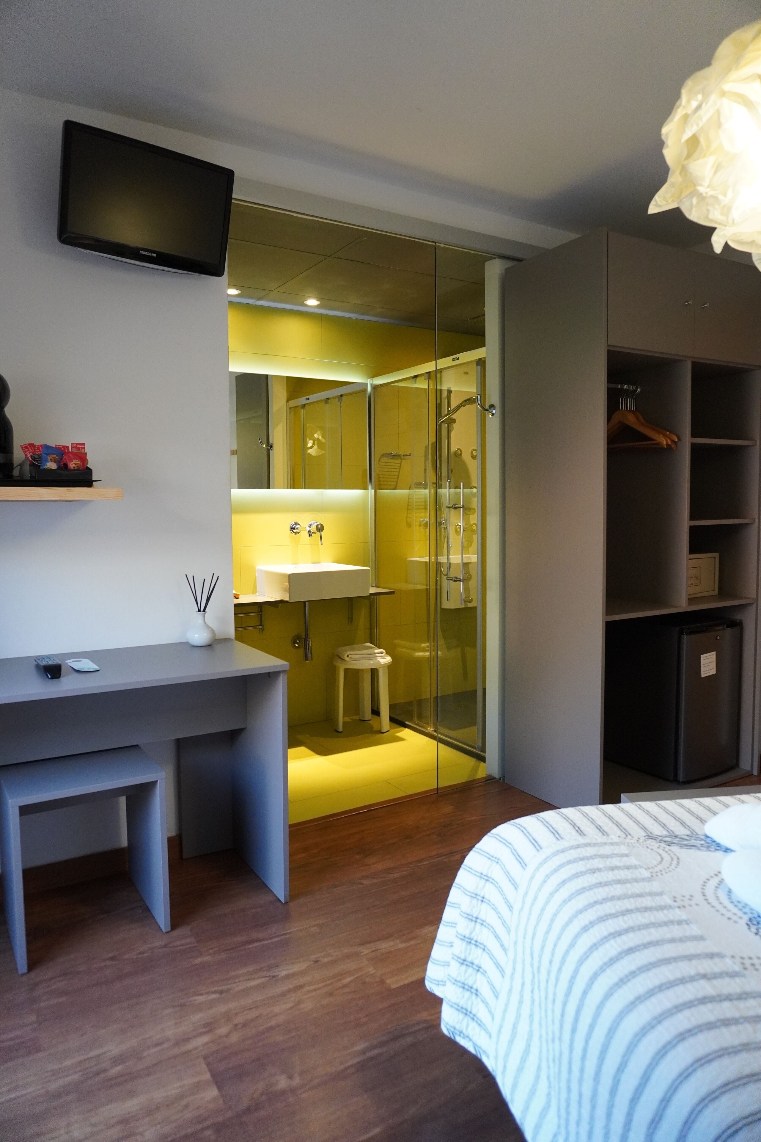 Ein modernes Schlafzimmer mit Bett, Schreibtisch, Fernseher und begehbarer Kleiderschrank.