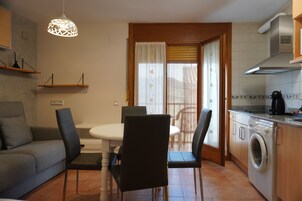 Una cocina compacta con lavadora, una mesa de comedor con sillas y un sofá.