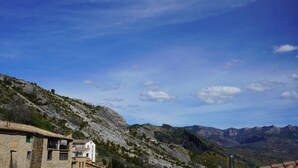 A mountainous landscape with traditional stone buildings, a clear sky, and distant mountains.