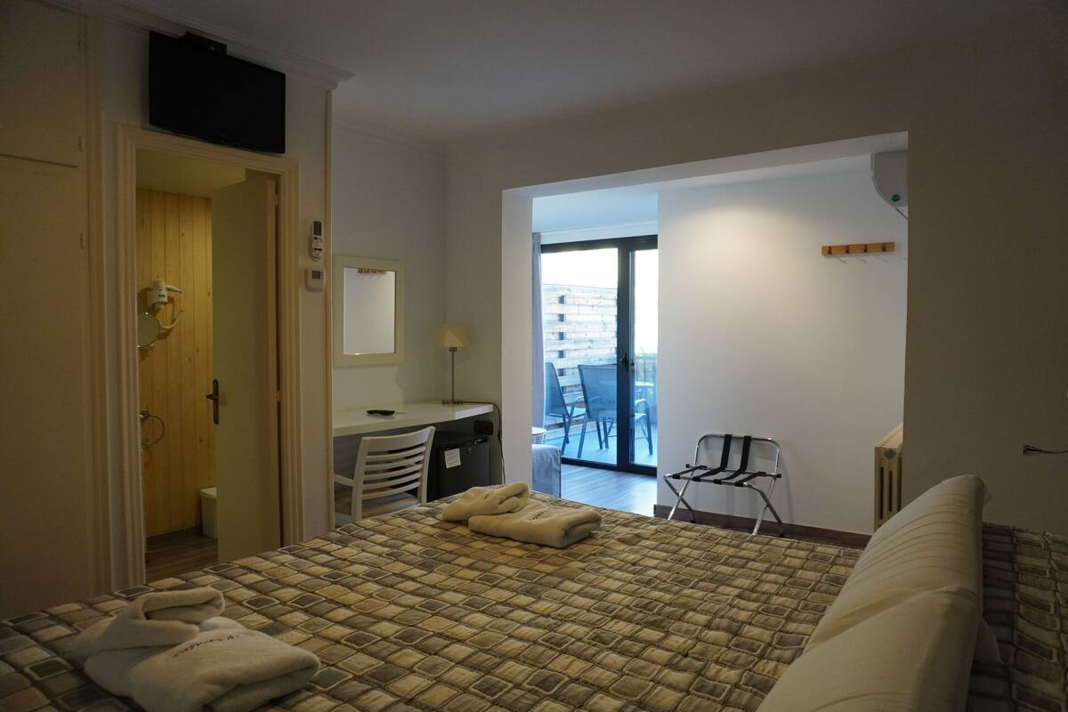 Et hotelværelse med seng, skrivebord, stol og udsigt ud