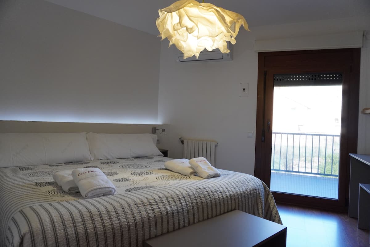 Et hotelværelse med seng, lille bord, balkondør og vindue.