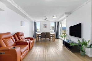 A modern living room with a sofa set, a dining table, and a TV.