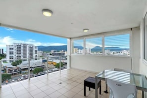 A balcony with a city view, a table, and a chair.