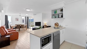 A modern apartment with a kitchen, dining area, and living room. - McLeod Rise—Cairn Base with Rooftop Pool & Spa (Cairns)