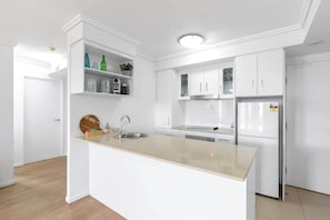 Una cucina moderna con mobili bianchi, un'isola centrale con lavello e forno integrato.
