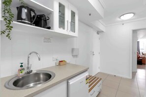 Une cuisine moderne équipée d’un évier en acier inoxydable, d’une machine à café et d’un réfrigérateur.