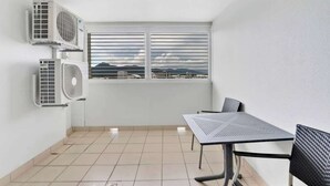 A small room with two air conditioning units, a window with a view, a tiled floor, and a table with chairs. - McLeod Nook—Poolside Studio by Waterfront & Market (Cairns)