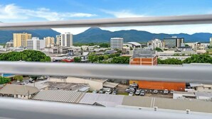A cityscape with buildings, a parking lot, and mountains in the background. - McLeod Nook—Poolside Studio by Waterfront & Market (Cairns)