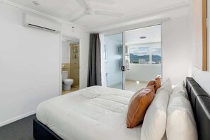 Una camera d'hotel con un letto, un bagno e una porta scorrevole in vetro che dà su un balcone.