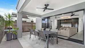 Une terrasse extérieure avec une table et des chaises, un canapé et des ventilateurs de plafond.