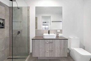 Un bagno moderno con box doccia in vetro, lavandino bianco e servizi igienici.