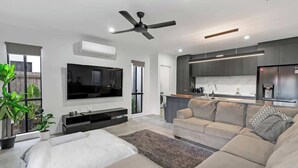 Un salon moderne avec un canapé, un téléviseur et un ventilateur de plafond.