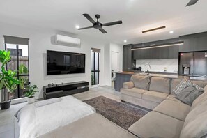 Un soggiorno moderno con divano, televisore e ventilatore a soffitto.