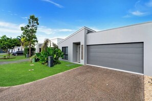 A modern residential building with a garage, a well-maintained lawn, and a driveway.