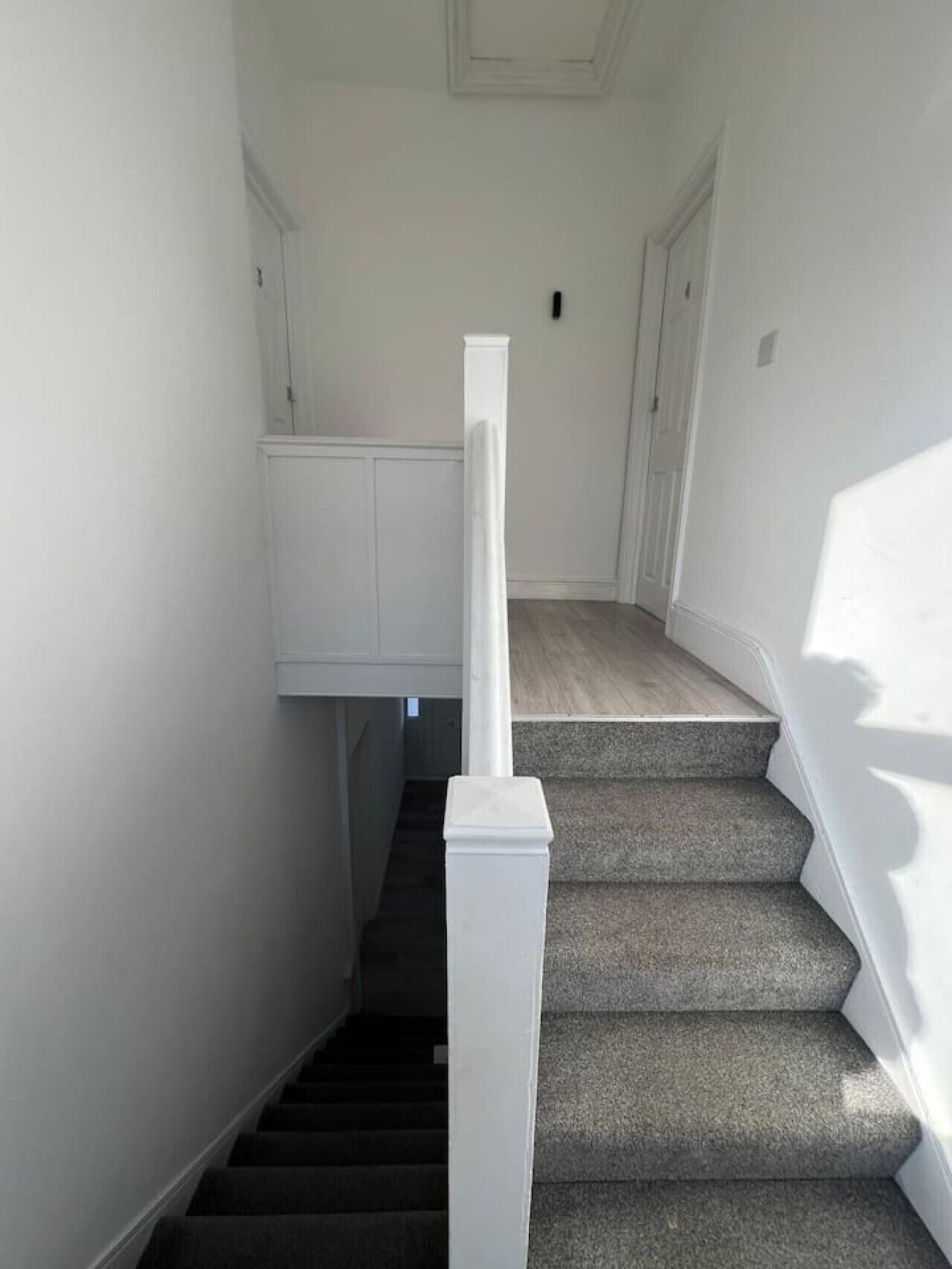 A staircase with carpeted steps and white handrails, leading to a door with a white frame.