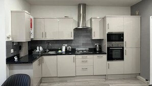 Une cuisine moderne avec des armoires blanches, une hotte de cuisinière en acier inoxydable, un four à micro-ondes et un four traditionnel.