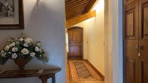 A hallway with a wooden door, a framed picture on the wall, and a floral arrangement on a table. - Villa Valmarana De Toni-Dimora Storica (Creazzo)