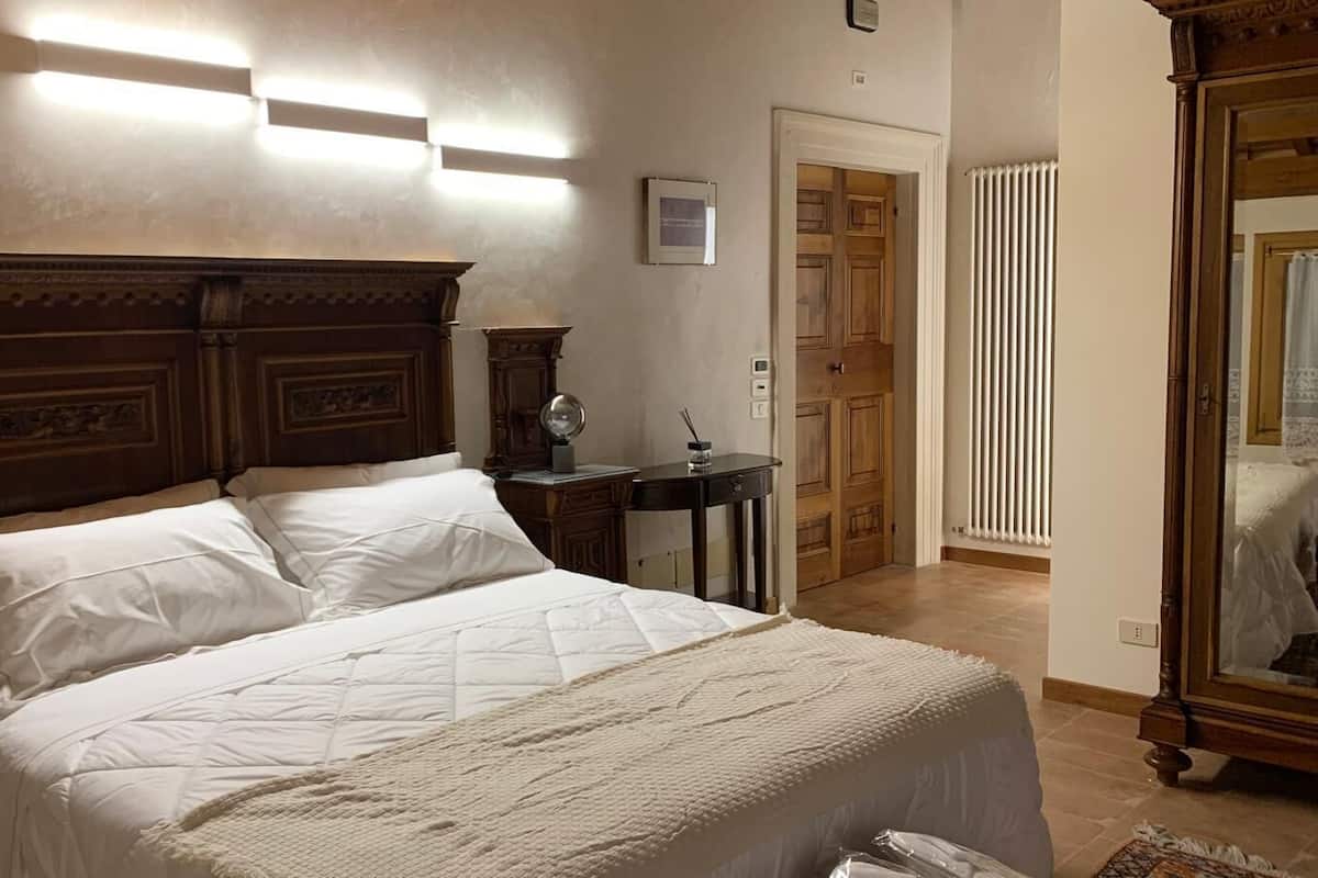 Une chambre à coucher avec un grand lit, une table de chevet, une commode et un miroir.