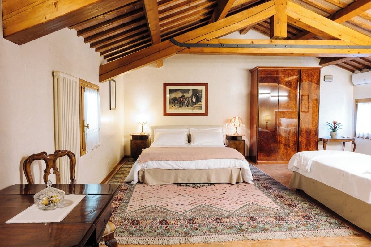 Une chambre à coucher comprenant un lit, une table de chevet, une armoire en bois, un miroir et un tapis à motifs.