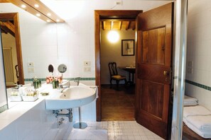 Une salle de bain avec un grand lavabo, un miroir et une porte en bois.