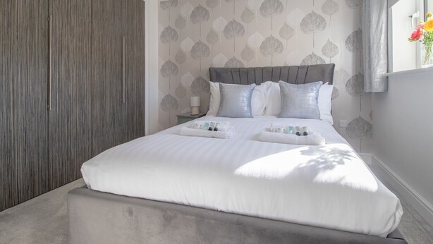 A modern bedroom with a large bed, a bedside table, a lamp, and a wardrobe. - Pass the Keys | Next to Braehead - Free Parking (Renfrew)