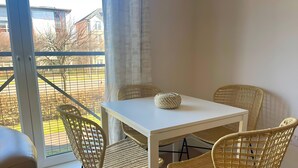 A balcony with a white table and wicker chairs, overlooking a brick wall and buildings. - Pass the Keys | Next to Braehead - Free Parking (Renfrew)