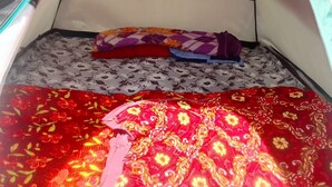 A tent with a patterned floor mat, a red and yellow floral blanket, and a purple and orange blanket. - Neelkanth camp Kedarnath (Kedarnath)