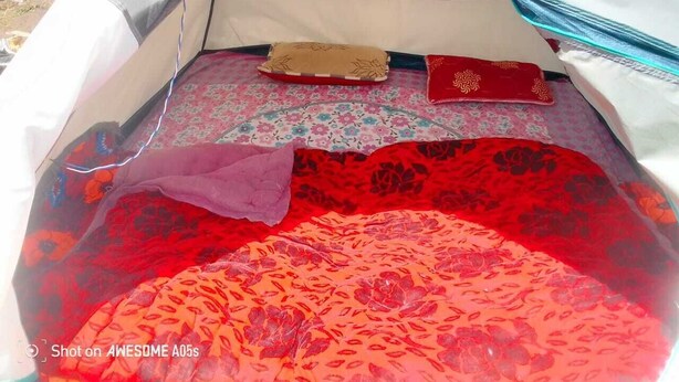 A tent with a patterned interior, a cushion, and a red book. - Neelkanth camp Kedarnath (Kedarnath)