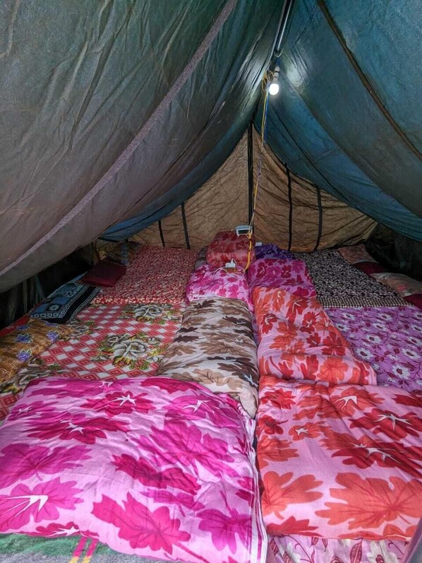 A tent with a sleeping area featuring colorful floral bedding. - Neelkanth camp Kedarnath (Kedarnath)