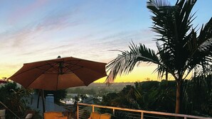 A hot tub with a wooden deck, outdoor seating with cushions, and a large umbrella. - Resort-Style Home for Families: Pool, Theater, Arcade, Hot Tub, Central location (San Diego)