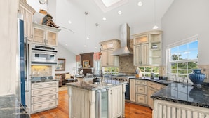 A spacious kitchen with a central island, built-in appliances, and a large window providing natural light.