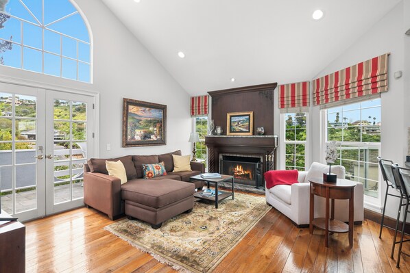 A spacious living room with a fireplace, large windows, and a view of the outdoors.