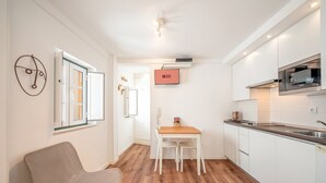 Una cocina moderna con armarios blancos, una mesa de comedor de madera y una silla.