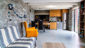 A modern kitchen with a stone wall, wooden cabinets, and a built-in fridge. - GuestReady – Rustic Charm in Peaceful Madeira (Porto da Cruz)