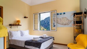 A bedroom with a bed, a map on the wall, a chair, and a shelf with items. - GuestReady – Rustic Charm in Peaceful Madeira (Porto da Cruz)