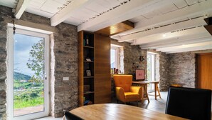 A modern interior with a wooden dining table, a bookshelf, and a chair. - GuestReady – Rustic Charm in Peaceful Madeira (Porto da Cruz)