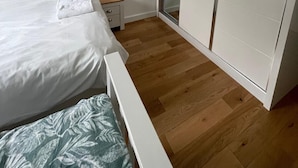 Un dormitorio con cama, mesita de noche, armario y puerta corrediza de vidrio.