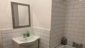Un baño con lavamanos, espejo y bañera blancos.
