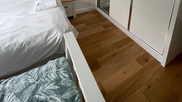 Un dormitorio con cama, mesita de noche, armario y puerta corredera de vidrio.