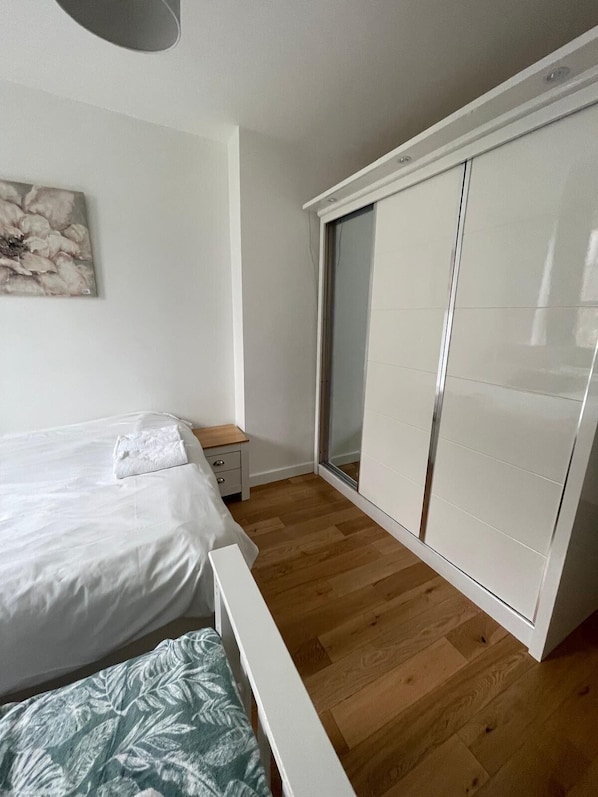 Quarto com cama, mesa de cabeceira, guarda-roupa e uma porta de vidro deslizante.
