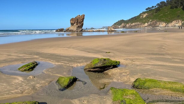 A beach with a prominent rock formation, clear skies, and calm waters. - APARTMENT IN MUROS DE NALÓN ASTURIAS (Muros de Nalón)
