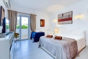 Ein Hotelzimmer mit Bett, Schreibtisch, Stuhl, Fernseher und Blick auf Grünflächen.