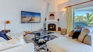 A modern living room with a fireplace, a large flat-screen TV, and a sofa. - Carvoeiro Pool House by Vacationy (Lagoa)