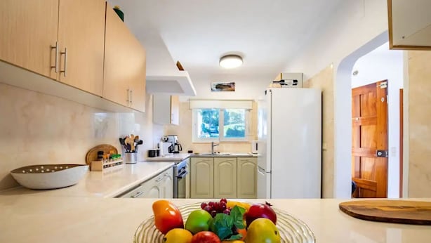 A modern kitchen with light wood cabinets, a white countertop, and a fruit bowl. - Carvoeiro Pool House by Vacationy (Lagoa)