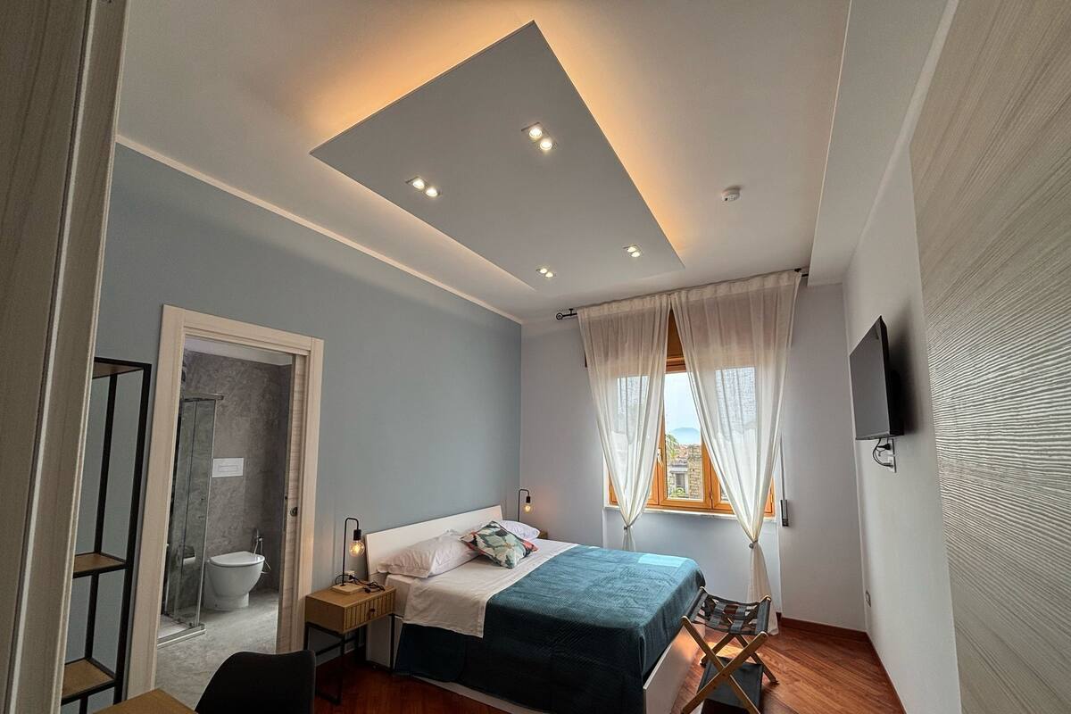 A modern bedroom with a bed, bedside table, and a TV mounted on the wall.