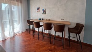 A modern dining area with a wooden table and four chairs, a light blue accent wall, and artwork. - Caridei Rooms (Naples)