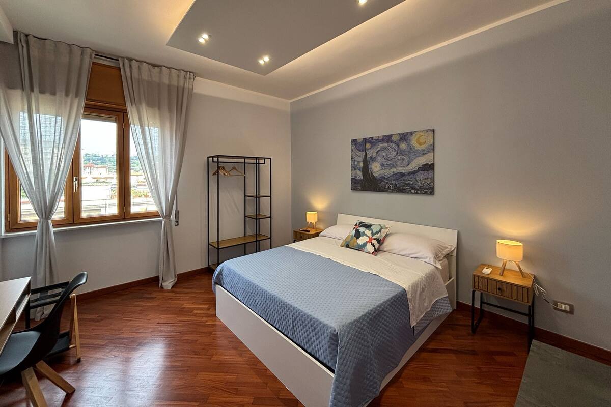 A bedroom with a bed, bedside tables, a wardrobe, and a painting on the wall.