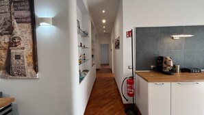 A modern kitchen with white cabinetry, a coffee machine, and a tea station. - Caridei Rooms (Naples)